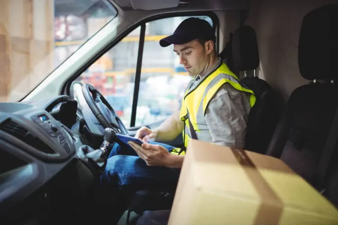 Delivery driver checking a package while sitting in a van
